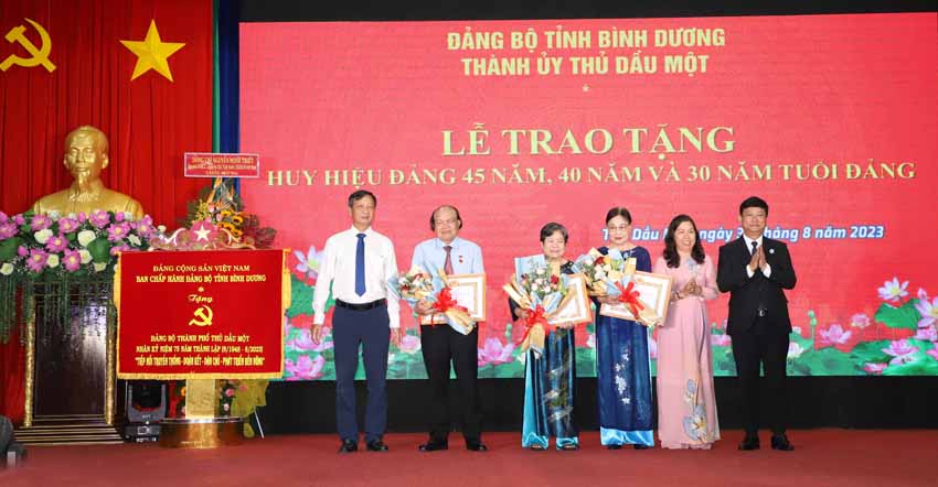 9; Ông Võ Văn Minh; ông Võ Văn Bá, Ủy viên Thường vụ, Trưởng Ban Nội chính Tỉnh ủy và bà Võ Thị Bạch Yến, Phó Bí thư Thường trực Thành ủy Thủ Dầu Một trao tặng Huy hiệu 40 năm tuổi Đảng cho các đảng viên